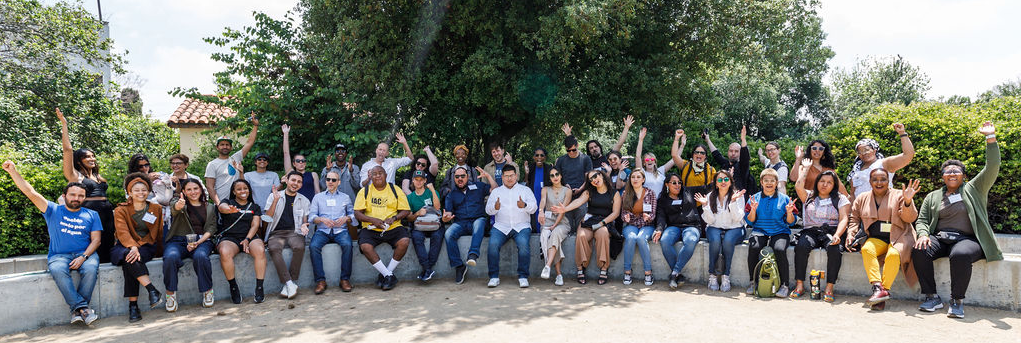 Group photo of 60 members of the Water Equity & Climate Resilience Caucus in front of a row of trees.